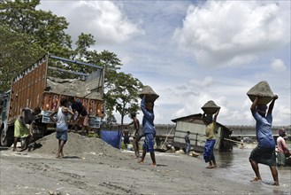 Labourer carries extracted sand from Beki River, in Barpeta district in Assam, India on Sunday