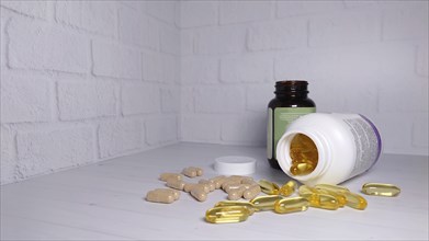 Supplements and pills scattered on a white surface with two bottles, one transparent and one