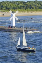 Sailboat passing the lighthouse when entering the port of Swinoujscie, Swinemünde, West Pomerania,