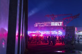 Festival visitors in front of an excavator with logo at the Melt Festival in Ferropolis on 12 July