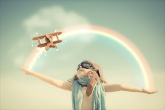 Happy kid playing with toy airplane against summer sky background