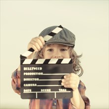 Kid holding clapper board in hands. Cinema concept. Retro style