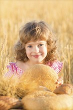 Happy child holding bread in hands against yellow autumn wheat field