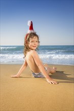 Happy child in Santa hat having fun at the tropical beach. Christmas holidays concept