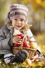 Happy child with basket of red apples in autumn park. Healthy lifestyles concept