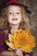 Happy kid holding autumn leaves. Halloween concept