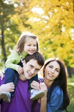 Happy family playing piggyback in autumn park