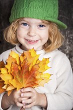 Happy smiling child holding yellow maple leaves. Autumn concept