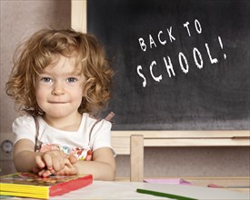 Happy smiling child in a class against blackboard with text