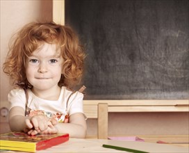 Funny smiling schoolchild in a class against blackboard