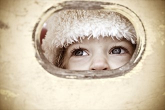 Child look out of hole in wooden background. Shallow depth of field