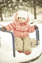 Beautiful baby playing on snow in winter park. Full length portrait, vintage toned