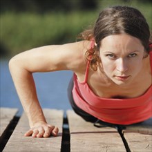 Strong sporty female doing push-ups outdoors