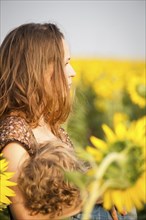 Young woman breastfeeding her baby in spring sunflower field