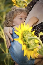 Baby breastfeeding in spring sunflower field