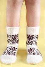 Children's feet in wool socks on a yellow background