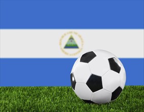 The Nicaragua flag and soccer ball on the green grass