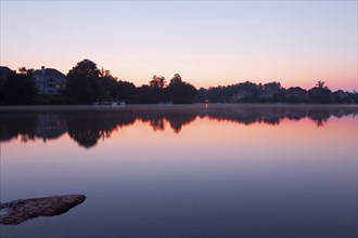 Lake landscape with houses. Misty sunrise