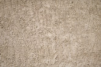 A close-up of a beige stucco wall with a rough textured surface