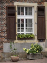 Detailed view of a house facade with window, shutters and planted flower pot, Legden, münsterland,