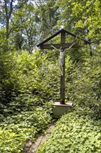 Old roofed cross with figure of Jesus Christ crucified on the cross at the edge of the forest,