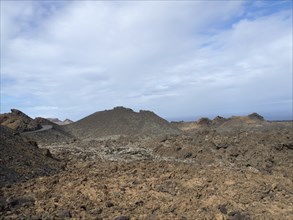 Extensive volcanic landscape with rocky hills under a blue-grey sky, arrecife, Lanzarote, Canary