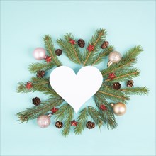 Christmas holiday background in heart shape, frame with fir branches, baubles and pine cones,