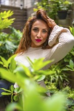 Portrait of an attractive Caucasian woman posing in a garden with plants enjoying nature in summer