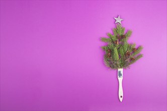 Christmas tree made from fir branches, pine cones and a painting brush as the trunk, pink greeting