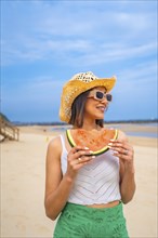 Portrait of middle eastern woman enjoying summer on the beach on vacation with a watermelon