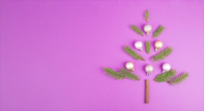 Christmas tree made from fir branches, pink baubles and a cinnamon stick as the trunk, greeting