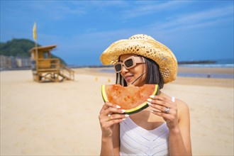 Middle eastern woman enjoying summer on the beach on vacation with a watermelon