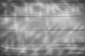 Wooden planks with shadowy light patterns creating a calm and subtle texture, background image