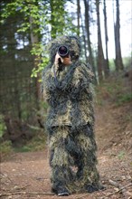 Photographer wearing camouflage clothing in the forest, wildlife animal photography with a camera