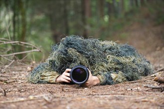 Photographer wearing camouflage clothing in the forest, wildlife animal photography with a camera