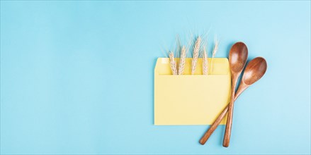 Envelope with wheat ears and empty spoons, food shortage and increasing prices, poverty through