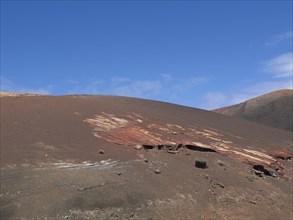 Red rocky landscape with barren ground and blue sky, arrecife, Lanzarote, Canary Islands, Spain,