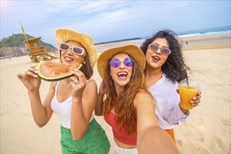 Selfie of multiethnic female friends enjoying summer on beach on vacation, outdoors smiling and