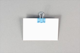 Blank white paper with a paperclip on a graycolored background, copy space for text, reminder or