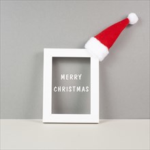 Frame with red Santa Claus hat, winter greeting card, merry christmas