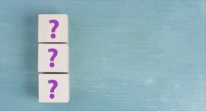 Three wooden cubes with question marks in purple color, searching for an answer, customer service