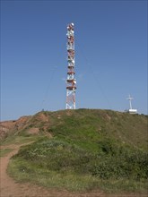 Radio tower on a green hill and an earthy path under a clear sky, Heligoland, North Sea, Germany,