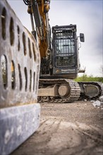 Demolition excavator on a construction site with metallic structures in the foreground and the