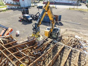 Aerial view of a construction site where an excavator is moving scrap and building material,