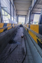 Long, narrow interior of a commercial hall with yellow protective markings on the sides, demolition