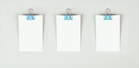 Blank white papers with a paperclip on a gray colored background, copy space for text, reminder or