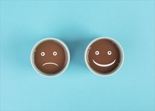 Cup of coffee with a sad and a happy face, positive and negative mindset, support and evaluation