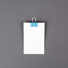 Blank white paper with a paperclip on a gray colored background, copy space for text, reminder or