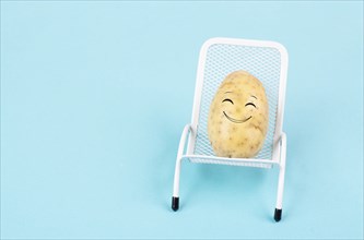 Potato with a funny face is sitting in lounge chairs, happy holiday, greeting card