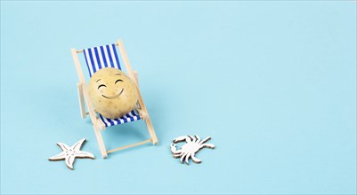 Potato with a funny face is sitting in lounge chairs, happy holiday, greeting card